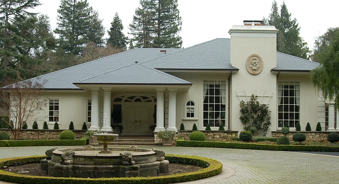 A large home with a neatly designed roof installed by Mid-Peninsula Roofing Inc. in Burlingame, featuring a front garden with a circular fountain.
